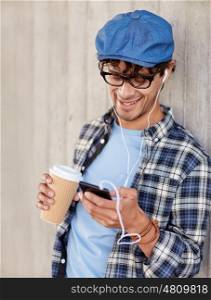 people, technology, leisure and lifestyle - close up of happy smiling man with earphones and smartphone drinking coffee and listening to music on city street