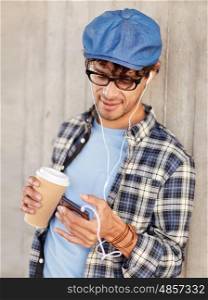 people, technology, leisure and lifestyle - close up of happy smiling man with earphones and smartphone drinking coffee and listening to music on city street