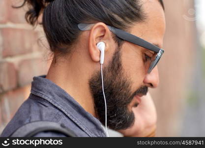 people, technology, leisure and lifestyle - close up of man with earphones listening to music outdoors