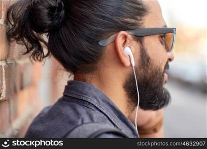 people, technology, leisure and lifestyle - close up of man with earphones listening to music outdoors