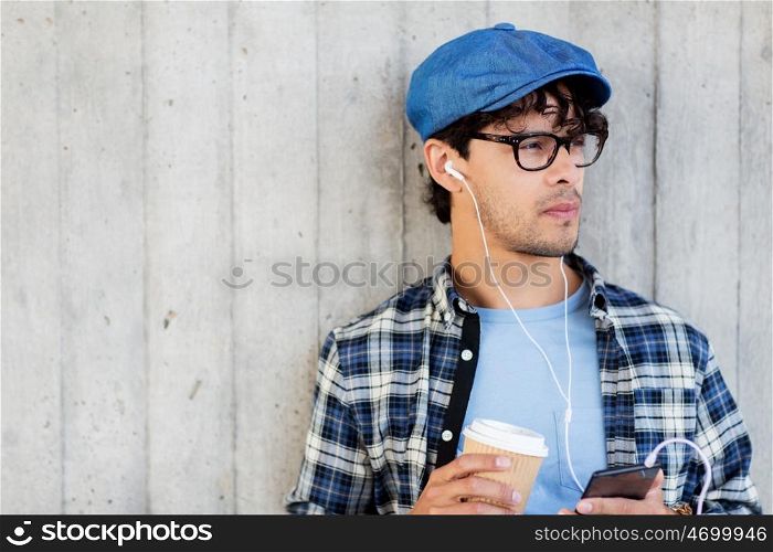 people, technology, leisure and lifestyle - man with earphones and smartphone drinking coffee and listening to music on city street