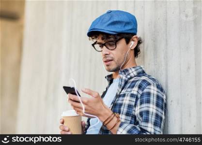 people, technology, leisure and lifestyle - man with earphones and smartphone drinking coffee and listening to music on city street
