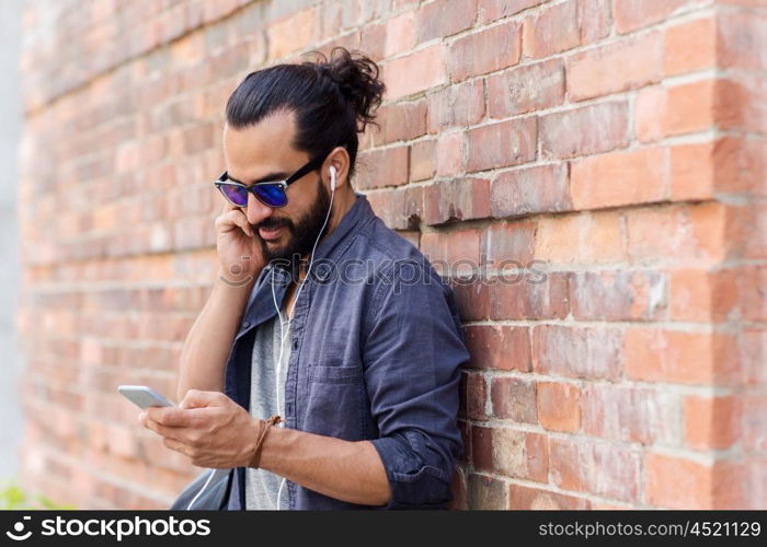 people, technology, leisure and lifestyle - man with earphones and smartphone listening to music on city street