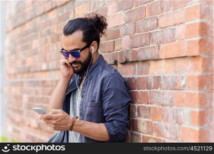 people, technology, leisure and lifestyle - man with earphones and smartphone listening to music on city street