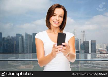people, technology, tourism and travel concept - young woman taking selfie with smartphone over singapore city background