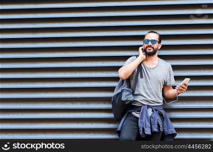 people, technology, travel and tourism - man with earphones, smartphone and bag on city street and listening to music