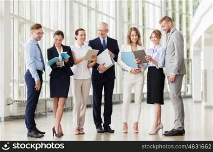 people, technology, work and corporate concept - business team with tablet pc computers and folders at office