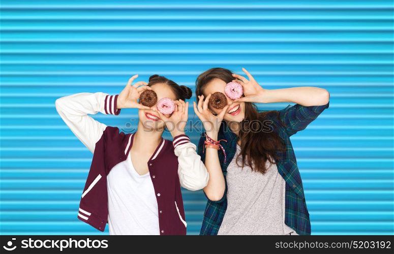 people, teens and fast food concept - happy smiling pretty teenage girls or friends with donuts making faces and having fun over blue ribbed background. happy pretty teenage girls with donuts having fun