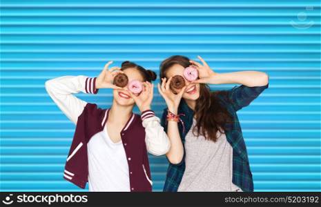 people, teens and fast food concept - happy smiling pretty teenage girls or friends with donuts making faces and having fun over blue ribbed background. happy pretty teenage girls with donuts having fun