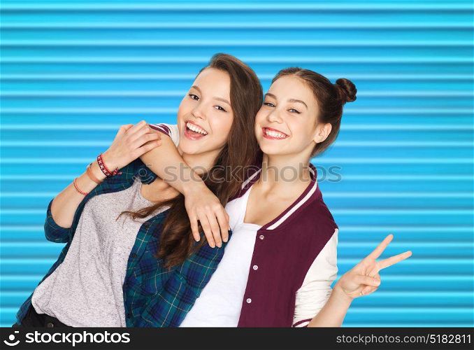people, teens and friendship concept - happy smiling pretty teenage girls or friends hugging and showing peace hand sign over blue ribbed background. happy teenage girls hugging and showing peace sign