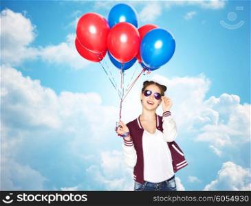 people, teens, holidays, party and summer concept - happy smiling pretty teenage girl in sunglasses with helium balloons over blue sky and clouds background