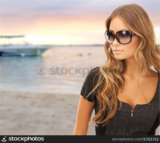 people, tourism and travel concept - beautiful young woman in shades over summer beach and boat background