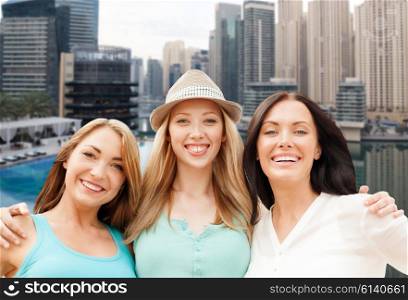 people, tourism, travel and vacation concept - happy young women looking up over dubai city harbour or waterfront with boats background