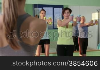 People training in fitness club, gym and sport activity. Group of women with instructor exercising with weights. 24of27