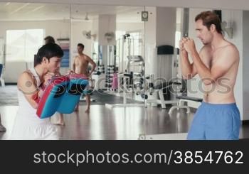 People training, working out, doing exercise in gym and fitness club, sports and martial art for wellness and wellbeing. Personal trainer and student, men doing kick boxing for self defense. 25of29