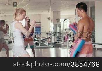 People training, working out, exercising in gym and fitness club, sport and martial arts. Personal trainer and student, man teaching boxing to woman for self-defense. Portrait looking at camera. 22of29