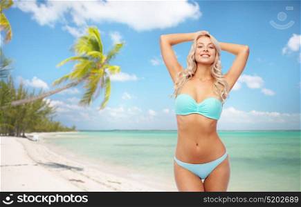 people, travel and summer holidays concept - happy smiling young woman in bikini swimsuit over exotic tropical beach with palm trees background. happy smiling young woman in bikini on beach