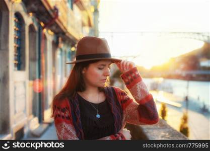 People, travel, holidays and adventure concept. Young woman with long hair walking on city street at sunrise, wearing hat and coat, enjoying happy pleasant moment of her vacations. Young woman with long hair walking on city street at sunrise, wearing hat and coat, enjoying happy pleasant moment of her vacations