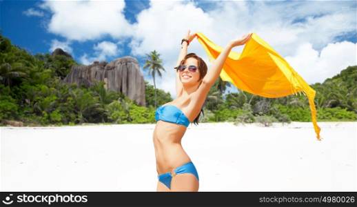 people, travel, summer holidays and vacation concept - beautiful woman in bikini and sunglasses with pareo over exotic tropical beach background. woman in bikini and sunglasses with pareo on beach