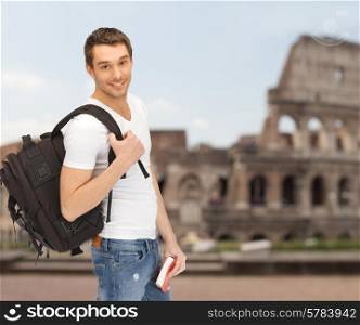 people, travel, tourism and education concept - happy young man with backpack and book travelling over coliseum background