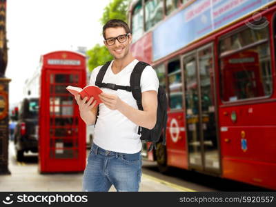 people, travel, tourism and education concept - happy young man with backpack and book over london city city bus on street background