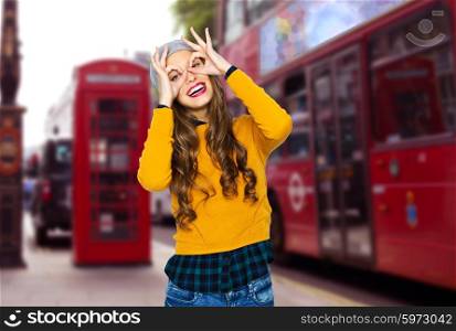 people, travel, tourism and fashion concept - happy young woman or teen girl in casual clothes and hipster hat having fun over london city street background