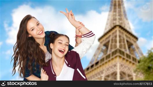 people, travel, tourism and friendship concept concept - happy smiling pretty teenage girls showing peace hand sign over eiffel tower in paris background