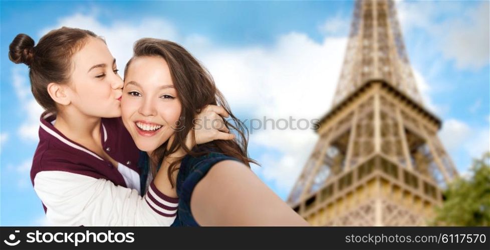people, travel, tourism and friendship concept - happy smiling pretty teenage girls taking selfie and kissing over eiffel tower in paris background