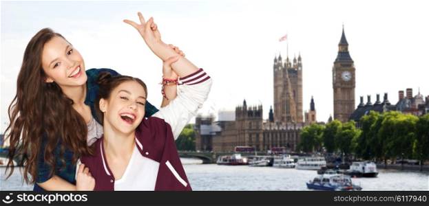 people, travel, tourism and friendship concept - happy smiling pretty teenage girls showing peace hand sign over london background