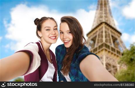 people, travel, tourism and friendship concept - happy smiling pretty teenage girls taking selfie over eiffel tower in paris background