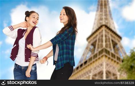 people, travel, tourism and friendship concept - happy smiling pretty teenage girls dancing over eiffel tower in paris background