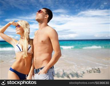 people, travel, tourism and summer holidays concept - happy couple in sunglasses over exotic tropical beach and ocean background. happy couple in sunglasses on exotic summer beach