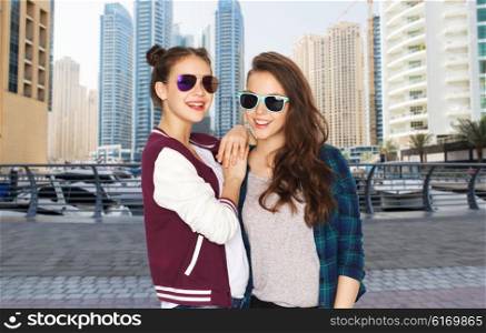 people, travel, tourism, fashion and teens concept - happy smiling pretty teenage girls oe friends in sunglasses over dubai city street background