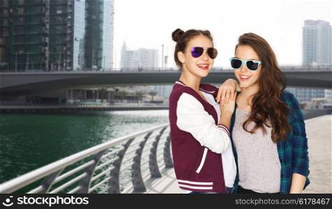 people, travel, tourism, fashion and teens concept - happy smiling pretty teenage girls oe friends in sunglasses over dubai city street background