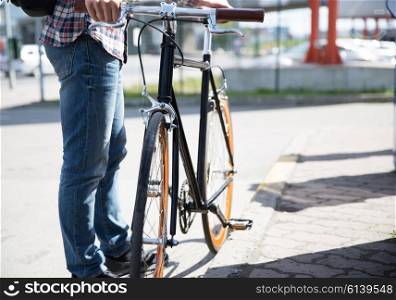 people, travel, tourism, leisure and lifestyle - close up of young hipster man with fixed gear bike on city street