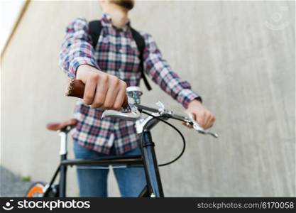 people, travel, tourism, leisure and lifestyle - close up of young hipster man with fixed gear bike and backpack on city street