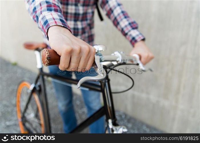 people, travel, tourism, leisure and lifestyle - close up of young hipster man hands holding fixed gear bike wheel on city street