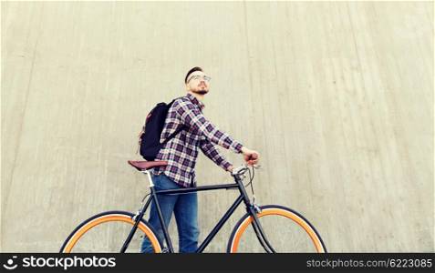 people, travel, tourism, leisure and lifestyle - happy young hipster man with fixed gear bike and backpack on city street