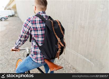 people, travel, tourism, leisure and lifestyle - young hipster man with fixed gear bike and backpack on city street