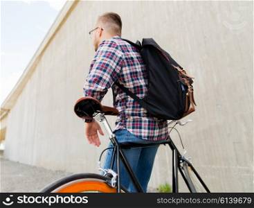 people, travel, tourism, leisure and lifestyle - young hipster man with fixed gear bike and backpack on city street