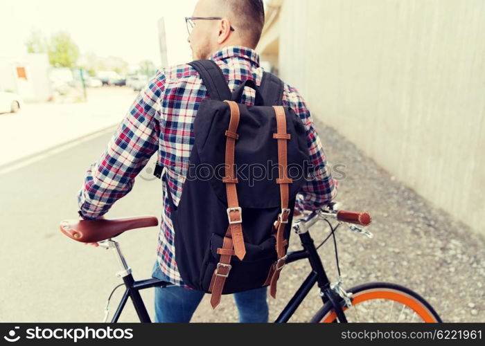 people, travel, tourism, leisure and lifestyle - young hipster man with fixed gear bike and backpack on city street