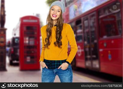 people, travel, tourism, style and fashion concept - happy young woman or teen girl in casual clothes and hipster hat over london city street background