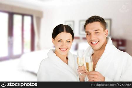 people, travel, tourism, vacation and honeymoon concept - happy couple in bathrobes over spa hotel room background