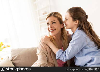 people, trust and family concept - happy daughter whispering secret to her mother at home. happy girl whispering secret to her mother at home