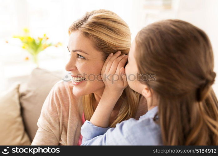 people, trust and family concept - happy daughter whispering secret to her mother at home. happy girl whispering secret to her mother at home