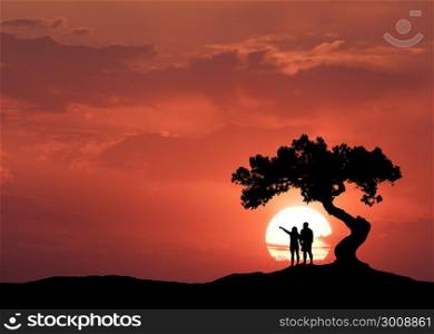 People under the crooked tree on the background of sun. Silhouette of a standing couple on the mountain, tree and colorful red sky with clouds at sunset. Beautiful landscape in the evening. Travel