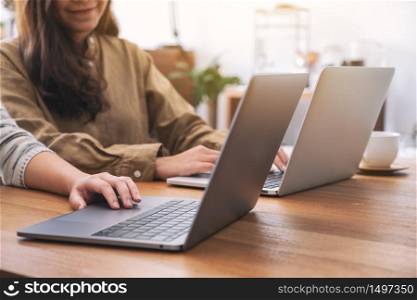 People using and looking at laptop computer on wooden table together