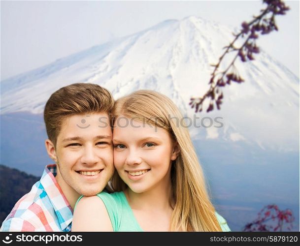 people, vacation, love and travel concept - smiling couple hugging over japan mountains background