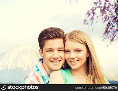 people, vacation, love and travel concept - smiling couple hugging over japan mountains background
