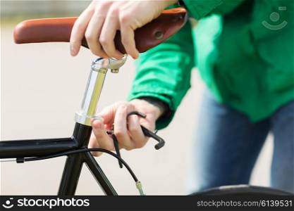 people, vehicle, eisure and lifestyle - close up of man adjusting fixed gear bike saddle high